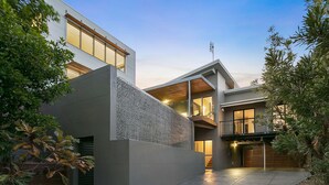 Ein modernes, zweistöckiges Haus mit Naturstein-Fassade, großen Fenstern und einer Garage.