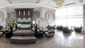 Un'ampia hall con un'area salotto centrale, grandi finestre e un moderno design del soffitto.