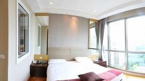 Camera d'albergo moderna con un letto grande, un comodino, una finestra con tende e vista sull'esterno.
