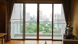 Una stanza con un'ampia porta-finestra scorrevole che si apre su un balcone con vista sulla città.