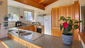 Una cocina con armarios de madera, encimera de granito, pileta, estufa y refrigerador.