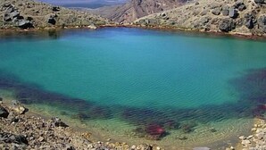 Un lago turquesa y transparente rodeado de terreno rocoso.