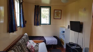 Una habitación pequeña y acogedora con cama, escritorio, televisor y ventana con cortinas.