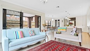 A modern living room with a light blue sofa, a white sofa, and a red patterned rug.