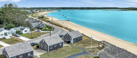 A coastal residential area with houses, a beach, and a clear blue sea.