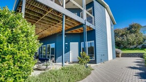 Una casa moderna de dos pisos con ático visible, ventanas amplias y entrada pavimentada.