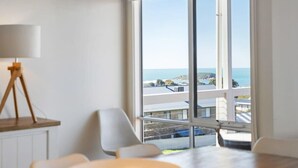 Una habitación moderna con un ventanal grande, una lámpara trípode y vistas al mar.