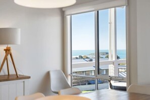 Una habitación moderna con un ventanal grande, una lámpara trípode y vistas al mar.