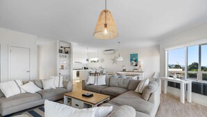Una sala de estar moderna con un sofá modular grande, una mesa de centro de madera y una lámpara colgante.