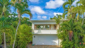 A two-story house with a garage, surrounded by lush greenery and palm trees. -  Steps to the Beach and a Stroll to Fort Lauderdale Nightlife  (Fort Lauderdale)