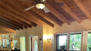 A living room with a black leather sectional sofa, a glass coffee table, and a wooden ceiling with exposed beams. -  Steps to the Beach and a Stroll to Fort Lauderdale Nightlife  (Fort Lauderdale)
