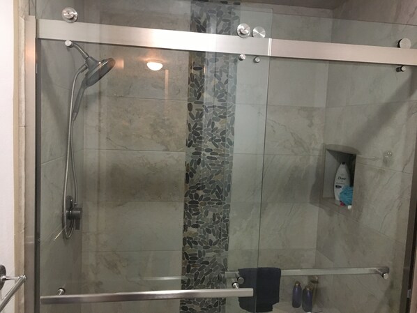 A glass-enclosed shower with a handheld showerhead and a handheld faucet. - Romantic Getaway for 2 in Cottage in complex right on the beach (Oceanside)