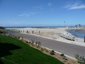 A coastal road with a grassy median, palm trees, and a clear view of the beach and ocean. - Romantic Getaway for 2 in Cottage in complex right on the beach (Oceanside)