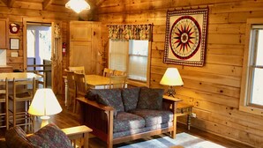 Interior acogedor de una cabaña con techo de madera, comedor, sofá y mesa de centro.
