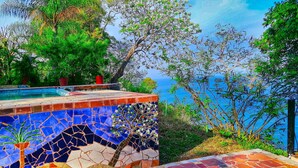 Un espace piscine doté d’un sol en mosaïque et offrant une vue sur la mer.