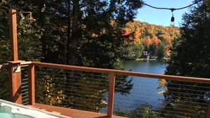A hot tub on a wooden deck with a view of a lake and autumn foliage. - 5 Bdrm Lakehouse, sleeps 18, private dock, hot tub, 15 minutes to Mount Snow (Wilmington)