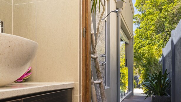 A modern bathroom with a large sink, a wooden ladder, and a view of a garden. - 5 Star Luxury Villa with Private pool (Scarborough)