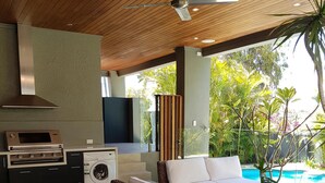 A modern outdoor living area with a sofa, a table, a ceiling fan, a built-in oven, and a washing machine. - 5 Star Luxury Villa with Private pool (Scarborough)