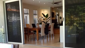 A modern interior with a dining area, a staircase leading to a balcony, and a view of the outdoors. - 5 Star Luxury Villa with Private pool (Scarborough)
