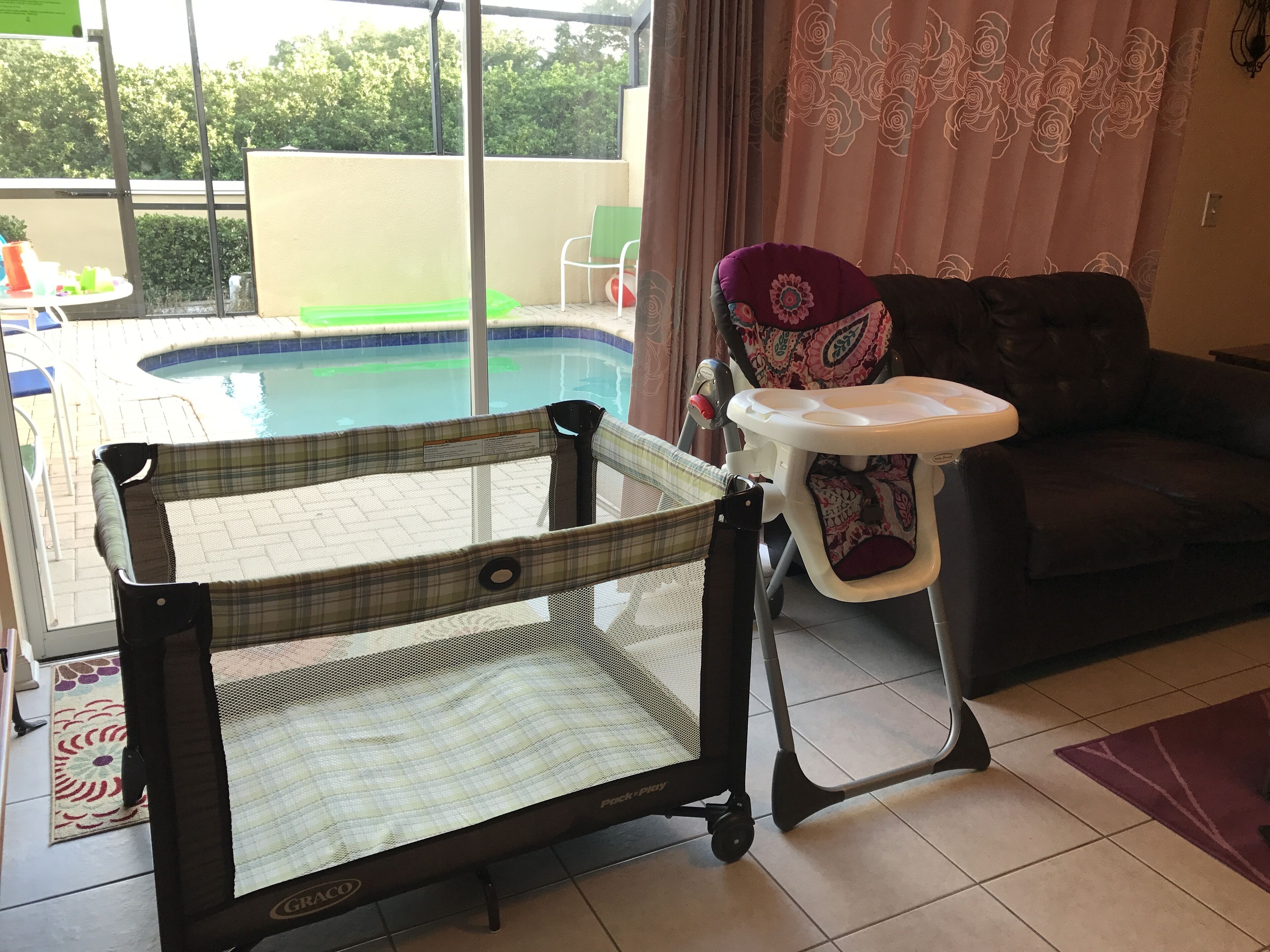 Quarto com vista para uma piscina, área de recreação infantil e um sofá.