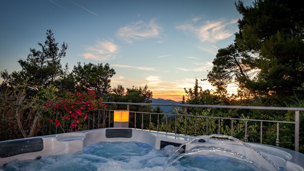 Ein Whirlpool mit Blick auf den Sonnenuntergang und die umliegenden Bäume.