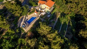 Eine Vogelperspektive auf ein Haus mit Swimmingpool, umgeben von dichtem Wald.