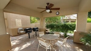 An outdoor patio with a round table and chairs, two barbecue grills, a ceiling fan, and a clock on the wall. - Beautiful central Scottsdale location, golf, restaurants  and very convenient. (Scottsdale)