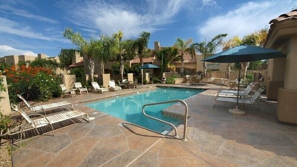 A swimming pool with lounge chairs and umbrellas, surrounded by palm trees and a clear sky. - Beautiful central Scottsdale location, golf, restaurants  and very convenient. (Scottsdale)