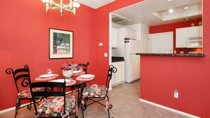A dining area with a red wall, a chandelier, and a table set for four with floral chairs. - Beautiful central Scottsdale location, golf, restaurants  and very convenient. (Scottsdale)