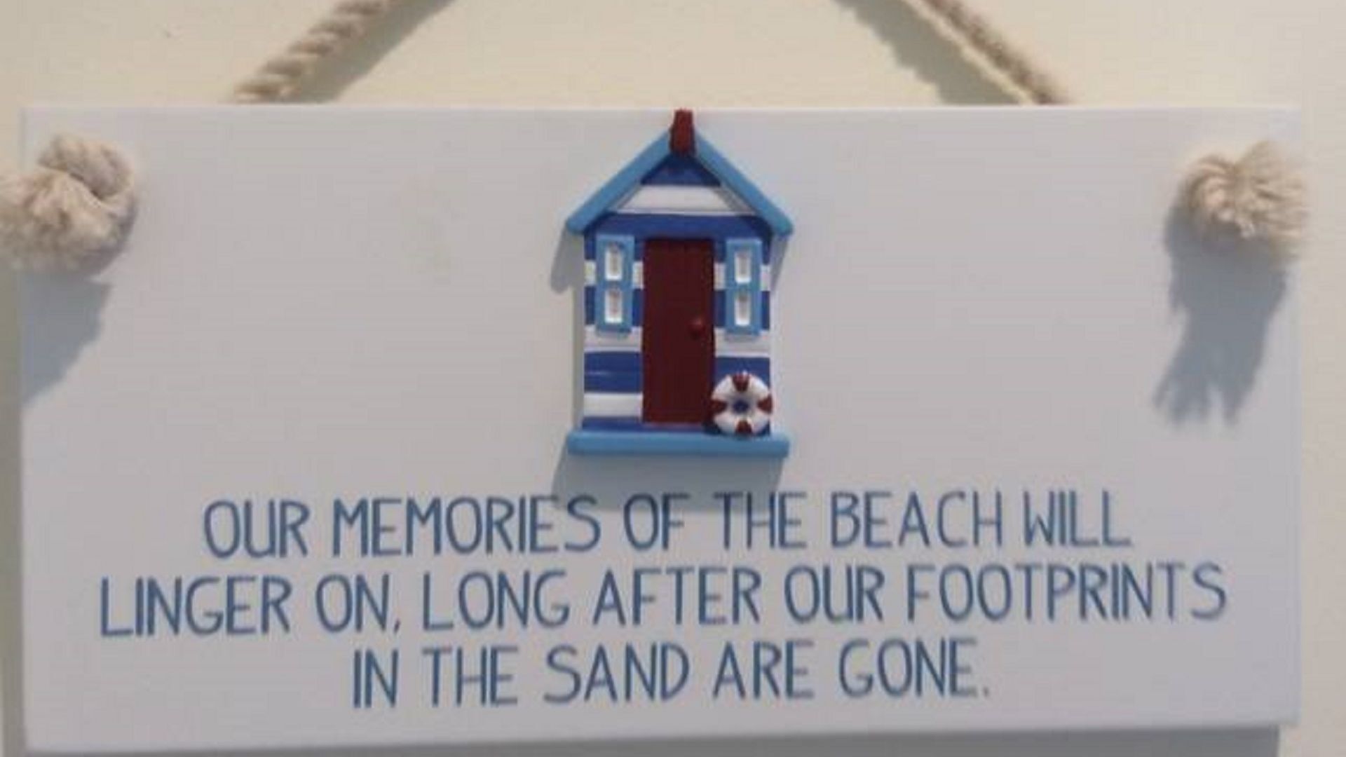 Ein Schild mit einer Hauszeichnung und Text über Strand Erinnerungen.