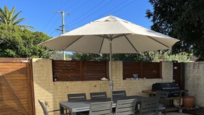 A patio with a table and chairs, an umbrella, a grill, and a wooden fence. - North Avoca Beach House
200m level walk to beach
4 bedrooms
secure yard (North Avoca)