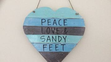 Eine herzförmige Dekoration mit dem Aufdruck "PEACE LOVE & SANDY FEET".