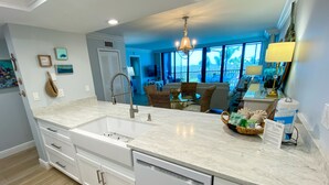 Una cocina moderna con una isla grande, armarios blancos y lavavajillas.