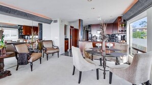 A spacious living area with a dining table, comfortable seating, and a view of the kitchen. - Corner Bayfront balcony, beach, parking, bikes (San Diego)