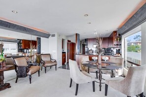A spacious living area with a dining table, comfortable seating, and a view of the kitchen.