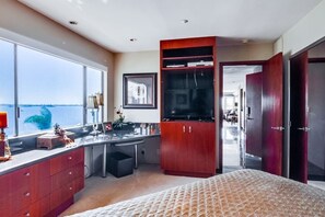A modern bedroom with a large window, a bed, a desk, and a wardrobe. - Corner Bayfront balcony, beach, parking, bikes (San Diego)