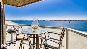 A balcony with a glass table, chairs, and a vase of nuts. - Corner Bayfront balcony, beach, parking, bikes (San Diego)