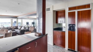 A modern kitchen with dark wood cabinets, a marble countertop, and a view of the sea through large windows. - Corner Bayfront balcony, beach, parking, bikes (San Diego)