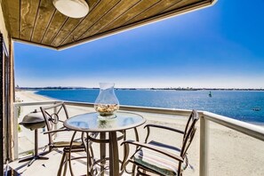 A balcony with a round table and chairs, overlooking a beach and the sea. - Corner Bayfront balcony, beach, parking, bikes (San Diego)