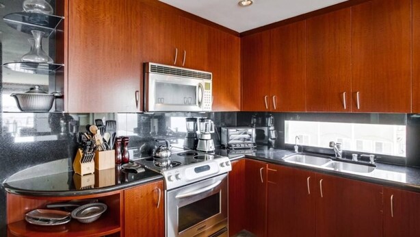 A modern kitchen with wooden cabinets, a stainless steel stove, and a microwave. - Corner Bayfront balcony, beach, parking, bikes (San Diego)