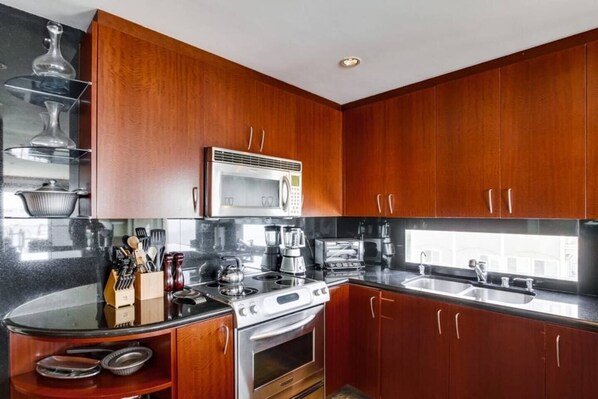 A modern kitchen with wooden cabinets, a stainless steel stove, and a microwave.