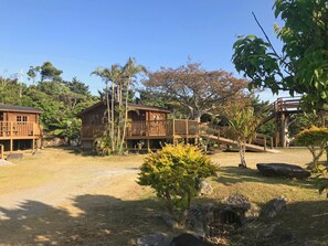 A wooden cabin with a balcony, surrounded by trees and a small garden. - Pension Yonahadake (Kunigami)