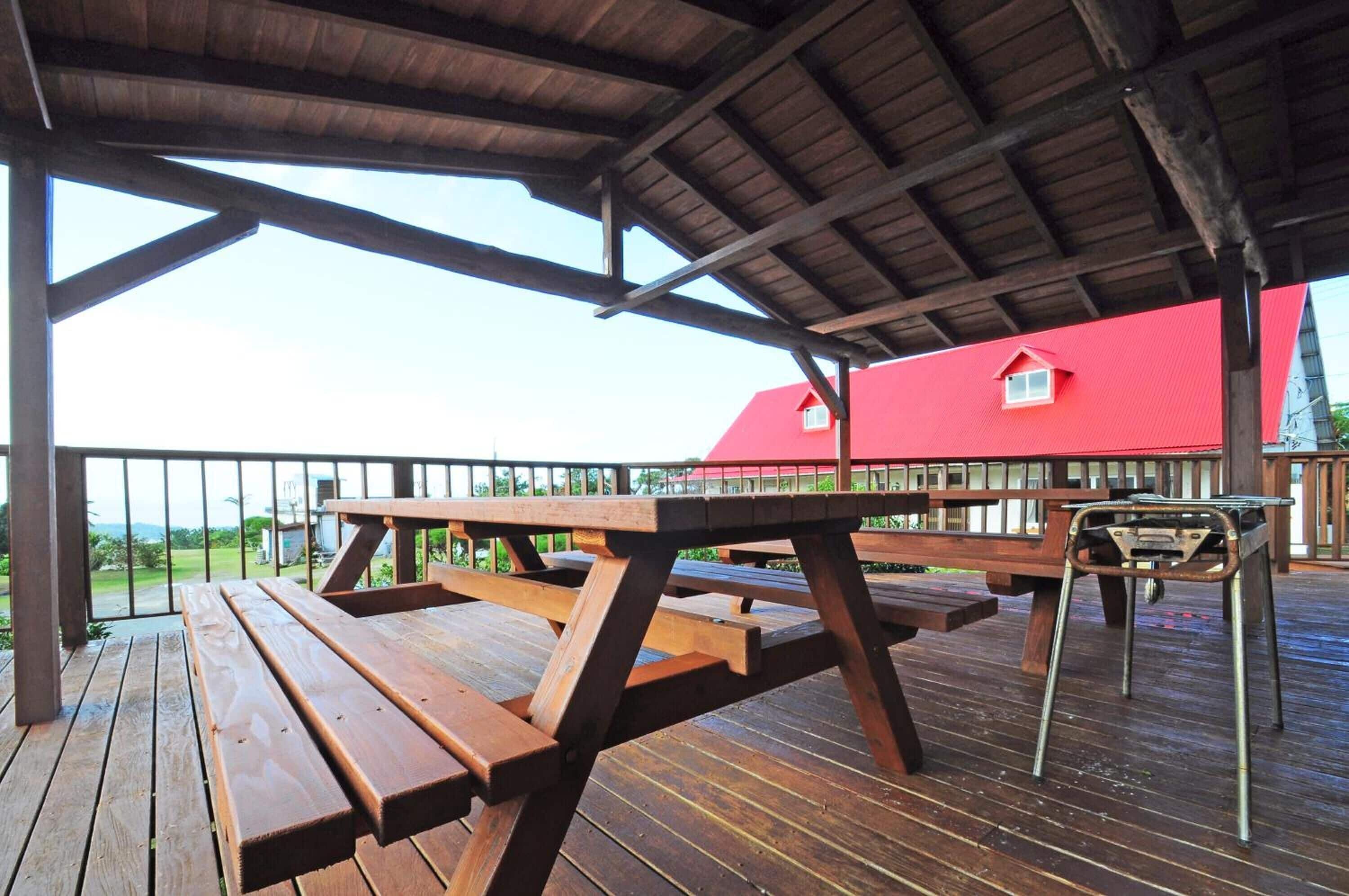 A wooden deck with picnic tables and a metal stool.