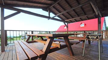 A wooden deck with picnic tables and a metal stool.