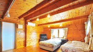 Un dormitorio de cabaña de madera con cama, mesita de noche y televisión.