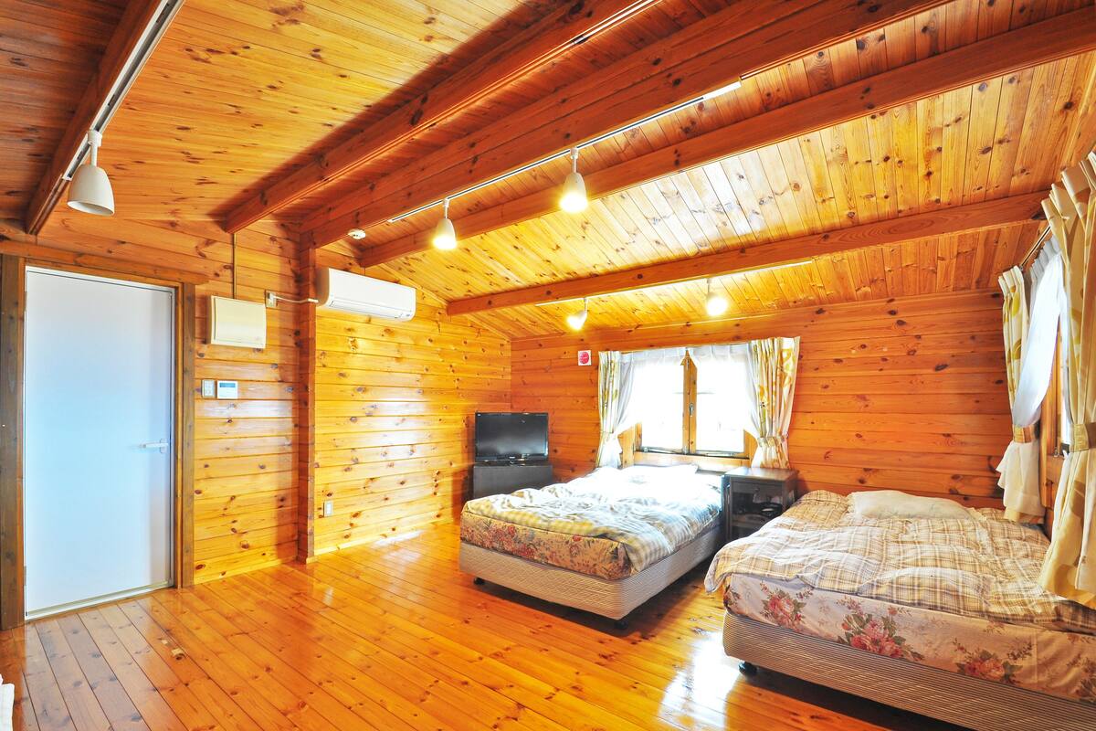 Ein Schlafzimmer einer Holzhütte mit einem Bett, einem Nachttisch und einem Fernseher.
