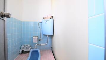 Un baño pequeño con un inodoro azul, un lavamanos y un cubo de basura.