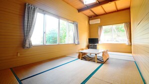 Una habitación japonesa tradicional con suelo de tatami, una mesa baja y un televisor.