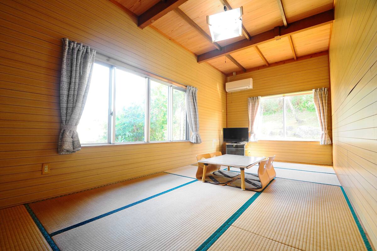 Ein traditioneller japanischer Raum mit Tatami-Bodenbelag, einem niedrigen Tisch und einem Fernseher.