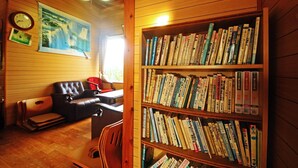 Una habitación acogedora con un sofá de cuero, una estantería llena de libros, un cuadro en la pared y un techo de madera.